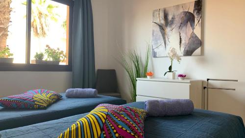 1 dormitorio con 2 camas azules y 2 ventanas en Bedroom with shared bathroom and swimming pool en Corralejo