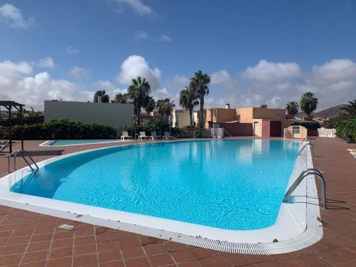 una gran piscina azul en un complejo en Bedroom with shared bathroom and swimming pool, en Corralejo