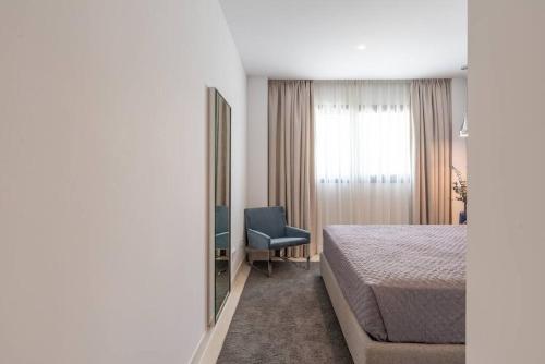 um quarto com uma cama, uma cadeira e um espelho em Lux Resort Higueron West VXL em Fuengirola