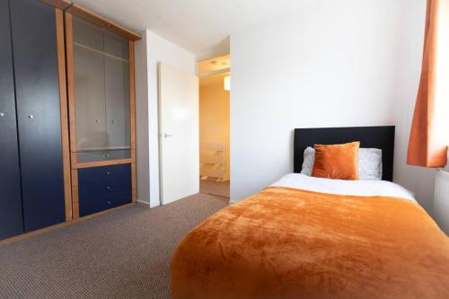 a bedroom with a large bed with an orange blanket at Ideal home with private parking for contractors & groups in Birmingham