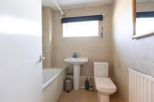 a bathroom with a toilet and a sink and a bath tub at Ideal home with private parking for contractors & groups in Birmingham