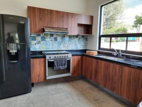 uma cozinha com armários de madeira e um frigorífico de aço inoxidável em Casa GaTo Tequisquiapan em La Tortuga