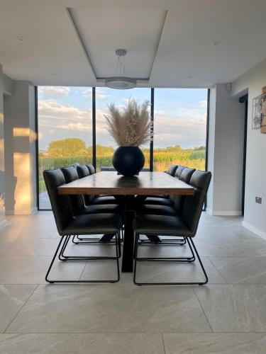 a dining room with a wooden table and chairs at Stunning modern home set in beautiful grounds. in Bath