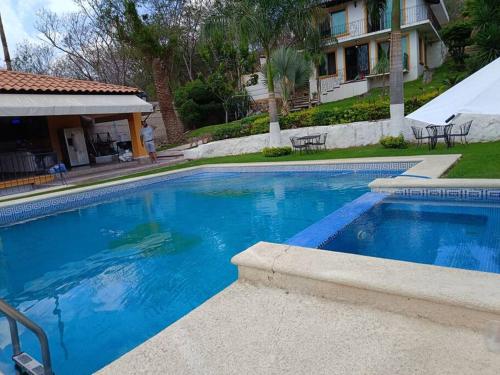 una gran piscina azul frente a una casa en Cabaña con terraza y alberca, en San José del Puente