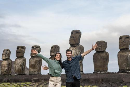 a man and a woman standing in front of a statue at Hotel Hare Uta in Hanga Roa