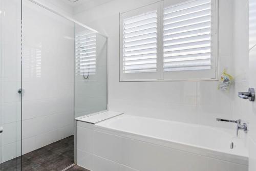 a white bathroom with a tub and a window at Seascape Christies Ocean Views in Christies Beach