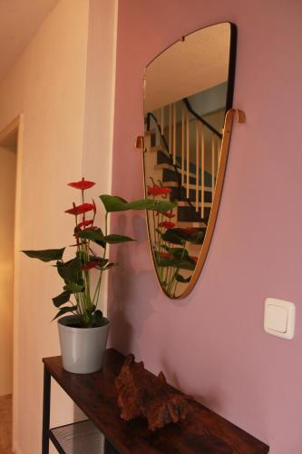 a mirror on a wall next to a table with a plant at Ferienwohnung CONNI in Hellenthal