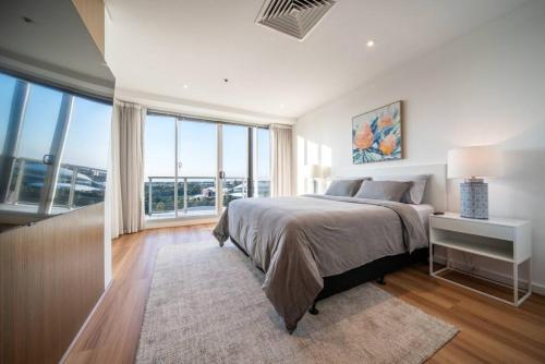 a bedroom with a large bed and large windows at The Views Penthouse Adelaide in Adelaide