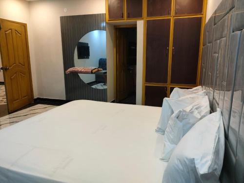 a bedroom with a white bed and a mirror at Hotel the Lodges inn in Multan