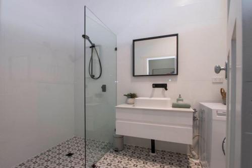 uma casa de banho branca com um lavatório e um espelho em Morris and Eaton Cottages - 3BR WiFi Parking em Colonel Light Gardens