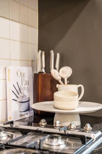 a kitchen counter top with a stove and a plate with spoons at Illuminate North Terrace - Executive CBD in Adelaide