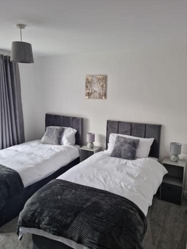 a bedroom with two beds and two tables with lamps at 5 bedroom house - Cheshire Oaks in Ellesmere Port