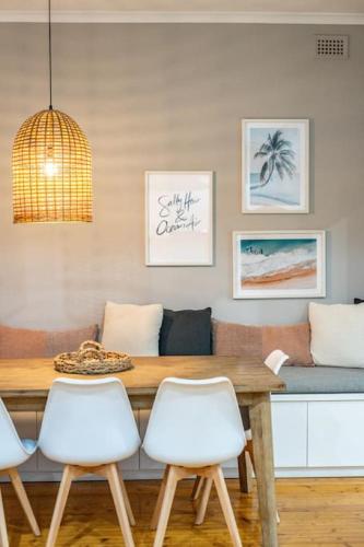 a dining room with a wooden table and white chairs at Seaside on Swan Laneway Retreat in Grange