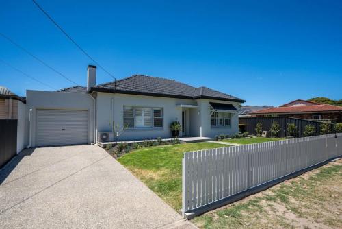 a white house with a fence in a yard at Seaside on Swan Laneway Retreat in Grange