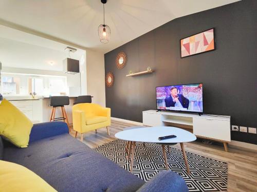 a living room with a blue couch and a tv at Joli T2 Scandi in Riom