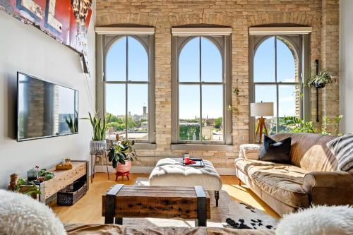 a living room with large windows and a brick wall at The Goatel - 1 bdrm apartment in Milwaukee
