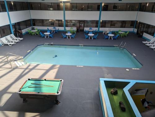 an empty pool in a building with tables and chairs at Woodfield Inn and Suites in Marshfield