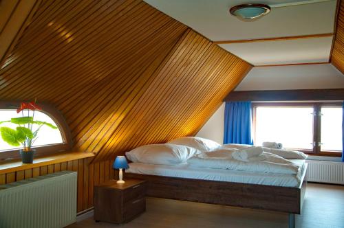 a bedroom with a bed with a wooden wall at Reetdachhaus -Seeblick - Ruhe - traumhafter Seeblick in Ostseebad Sellin