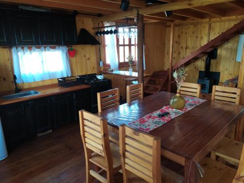 een keuken en eetkamer met een houten tafel en stoelen bij Cabañas en los reartes in Los Reartes