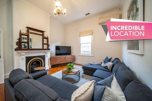 a living room with a blue couch and a fireplace at Irmas Place on Halifax in Adelaide