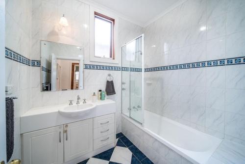 uma casa de banho branca com um lavatório e um chuveiro em Irmas Place on Halifax em Adelaide