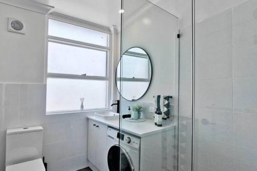 uma casa de banho com um chuveiro, um lavatório e um espelho. em Bloom at Lotus Apartments em Plympton