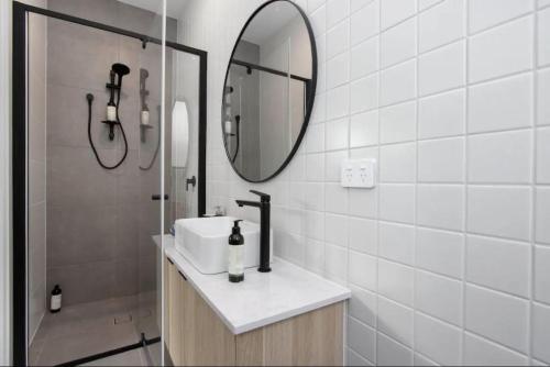 uma casa de banho com um lavatório, um espelho e um chuveiro em The West on Daphne Kurralta Park em Wayville