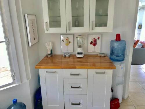 a kitchen with white cabinets and a counter with a refrigerator at Hidden Valley Villa in Teagues Bay