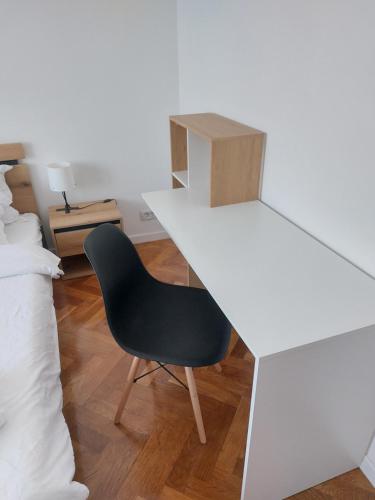 un escritorio blanco con una silla negra junto a una cama en ELI's Apartments, en Iaşi