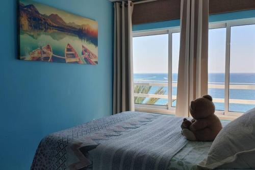 a teddy bear sitting on a bed in a bedroom at Coqueto loft con vistas inmejorables frente al mar in Alicante