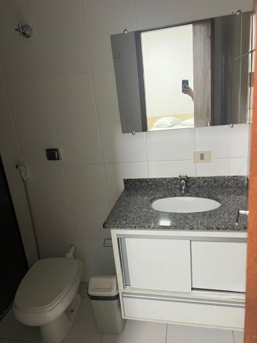 a bathroom with a toilet and a sink and a mirror at Versatile Park Hotel in Ponta Porã