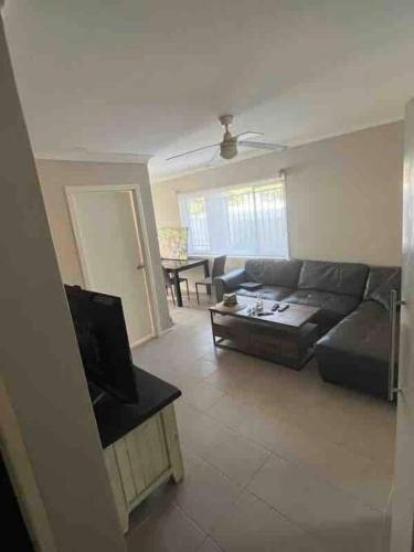 uma sala de estar com um sofá e uma televisão em Small Room in Shared Apartment U1S em Brisbane