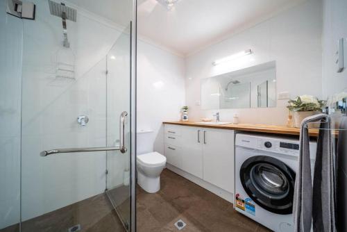 a bathroom with a shower and a washing machine at Plane Tree Cottage North Adelaide in Bowden
