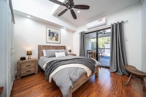 a bedroom with a bed and a ceiling fan at Plane Tree Cottage North Adelaide in Bowden