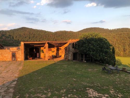 ein Steingebäude mit einer Bank im Gras in der Unterkunft Mas El Soler de Terrades - Turisme Rural in Moià