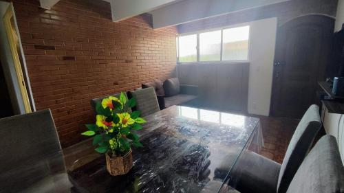 une salle à manger avec une table en verre et des fleurs. dans l'établissement Ao Lado do Aeroporto com vaga coberta, à Guarulhos