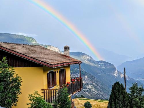 a rainbow over a yellow house with mountains in the background at Alpine Vista Villa Hardaker 4 bedrooms Torgnon in Torgnon