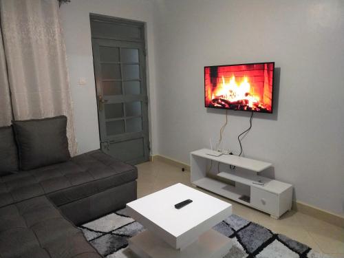 ein Wohnzimmer mit einem Sofa und einem TV an der Wand in der Unterkunft One bedroom apartments tulivu in Thika