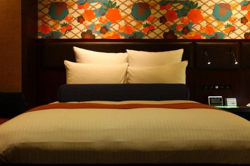 a bedroom with a large bed with a floral wall at Loisir Spa Tower Naha in Naha