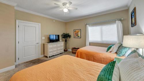 a bedroom with two beds and a flat screen tv at Harbor Landing 203B - Spacious Condo with views of the Harbor and Gulf in Destin