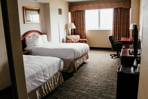 a hotel room with two beds and a chair at Hotel Topeka at City Center in Topeka