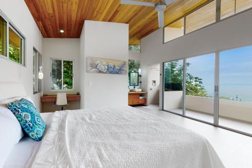 a bedroom with a large bed and large windows at Casa Sulit in Dominical