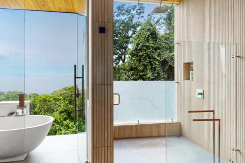 a bathroom with a tub and a shower with a glass door at Casa Sulit in Dominical