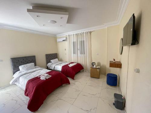 a bedroom with two beds and a flat screen tv at Royal Pyramids Museum Guest House in Cairo