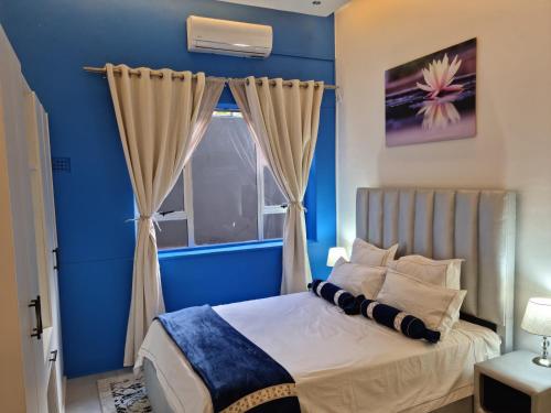 Dormitorio azul con cama y ventana en SapphireA@54, en Windhoek