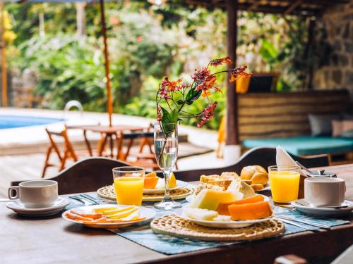 a table topped with plates of food and orange juice at VELINN Hotel Santa Tereza in Ilhabela