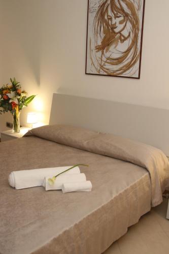 ein Bett mit zwei Handtüchern und einem Gemälde an der Wand in der Unterkunft DIMORAVIAPIADUE in Savona