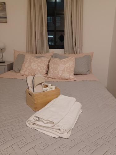 Una cama con una caja de zapatos y toallas. en Alexandra Guridy Room For Rent, en Los Tres Ojos de Agua