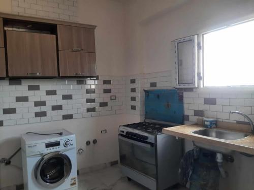 eine Küche mit einer Waschmaschine und einem Waschbecken in der Unterkunft فيلا محمد بدر in Naj‘ al Aḩwāl