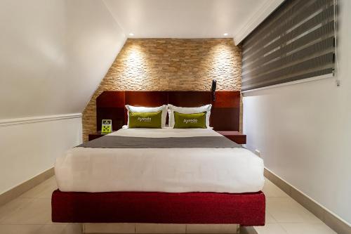 a bedroom with a large bed with green pillows at Lavid Hotel Palacio Real in Bogotá